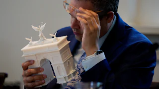 Matthew Taylor, a member of the Commission of Fine Arts, inspects a model of Trump’s proposed triumphal arch