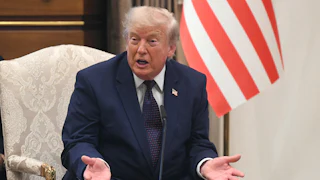 President Donald Trump speaking with his hands open on his lap