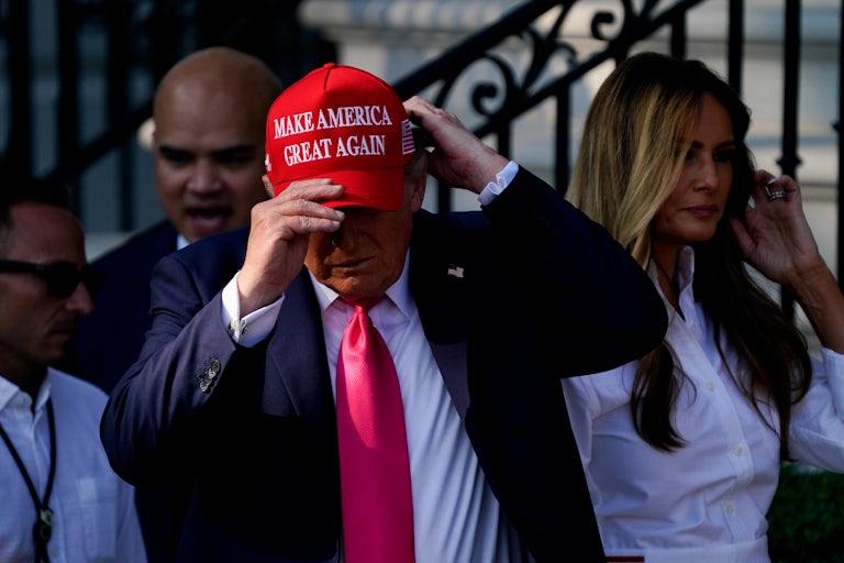 President Donald Trump puts on a MAGA hat.