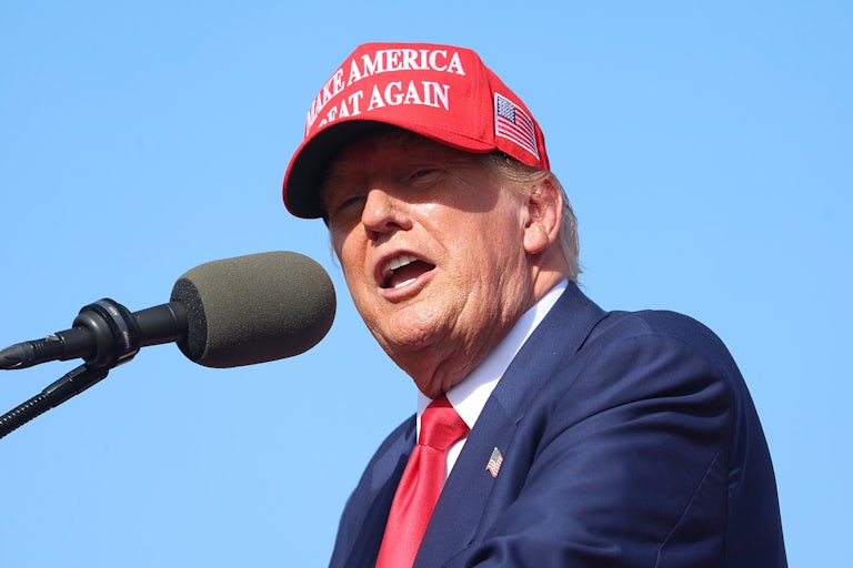 Donald Trump wears a Make America Great Again cap and speaks at a lectern