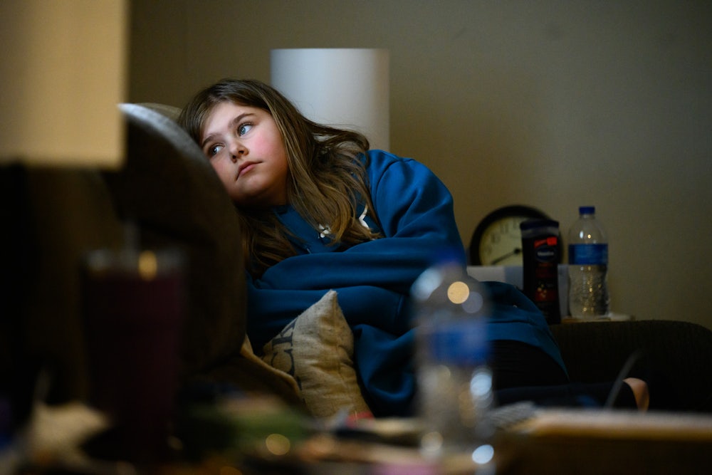A child sits in a chair, looking off to the side.