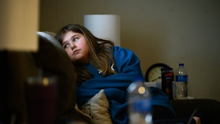 A child sits in a chair, looking off to the side.
