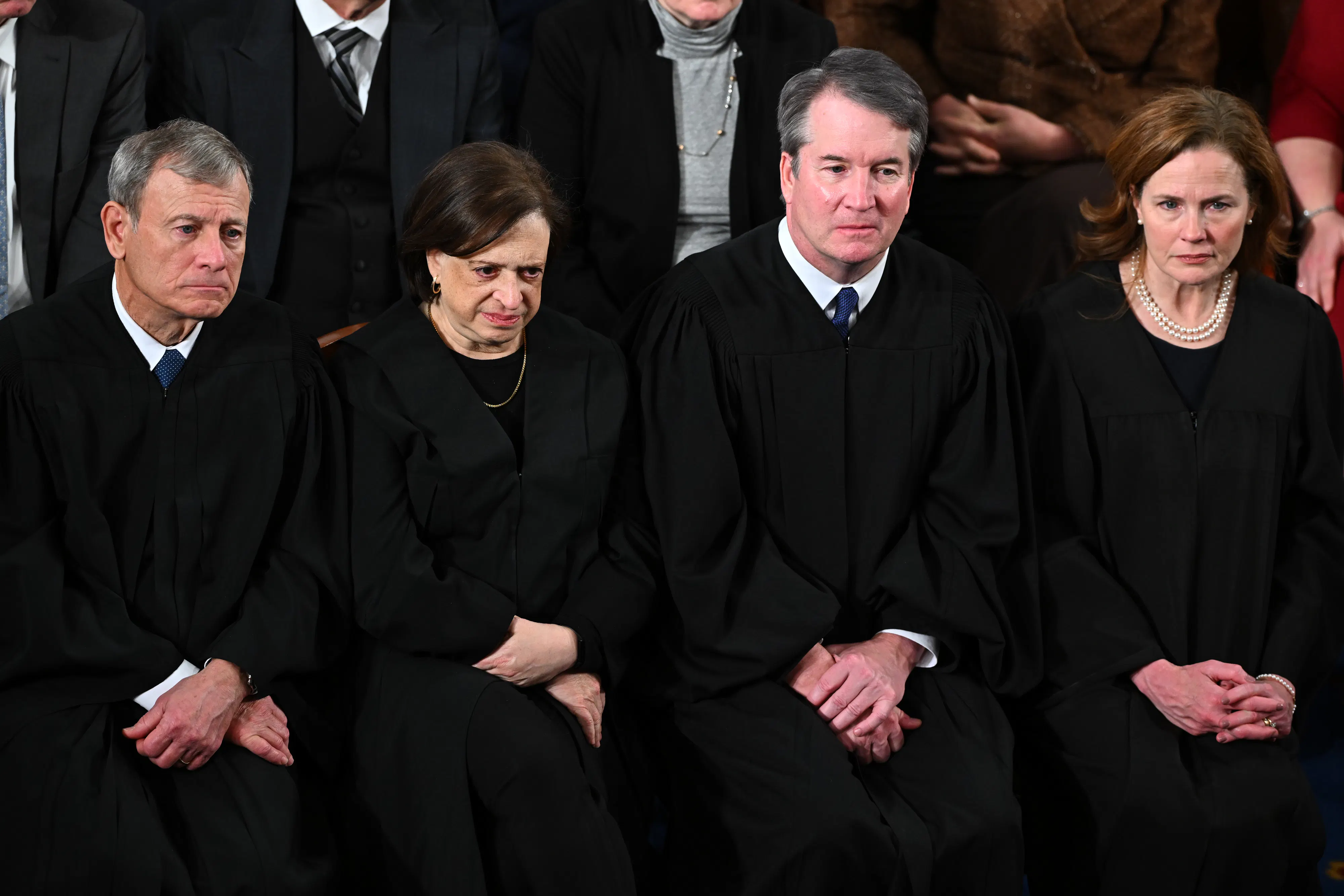 Supreme Court Justices John Roberts, Elena Kagan, Brett Kavanaugh, and Amy Coney Barrett sit side by side at Trump's State of the Union address in the Capitol.