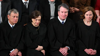 Supreme Court Justices John Roberts, Elena Kagan, Brett Kavanaugh, and Amy Coney Barrett sit side by side at Trump's State of the Union address in the Capitol.
