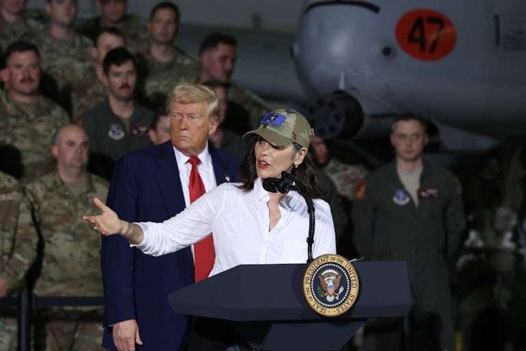 Donald Trump stands behind Gretchen Whitmer as she gestures and speaks onstage at one of his events