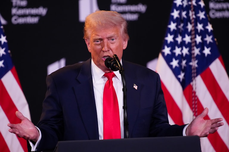 Donald Trump holds his hands out to the side while speaking at a podium at the Kennedy Center