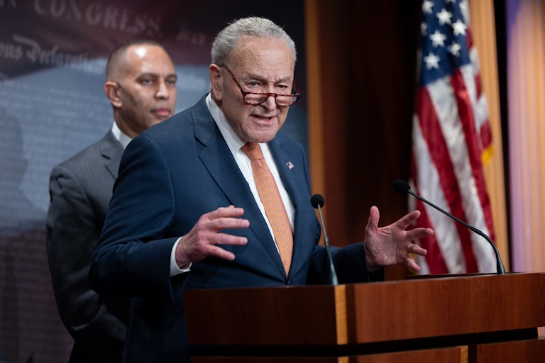 Chuck Schumer speaks at a podium as Hakeem Jeffries stands behind him