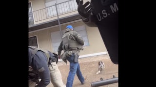 A screenshot of a U.S. Marshal approaching the dog before kicking it.