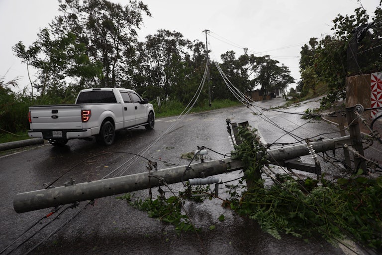 A pickup truck drives next to downed power lines.