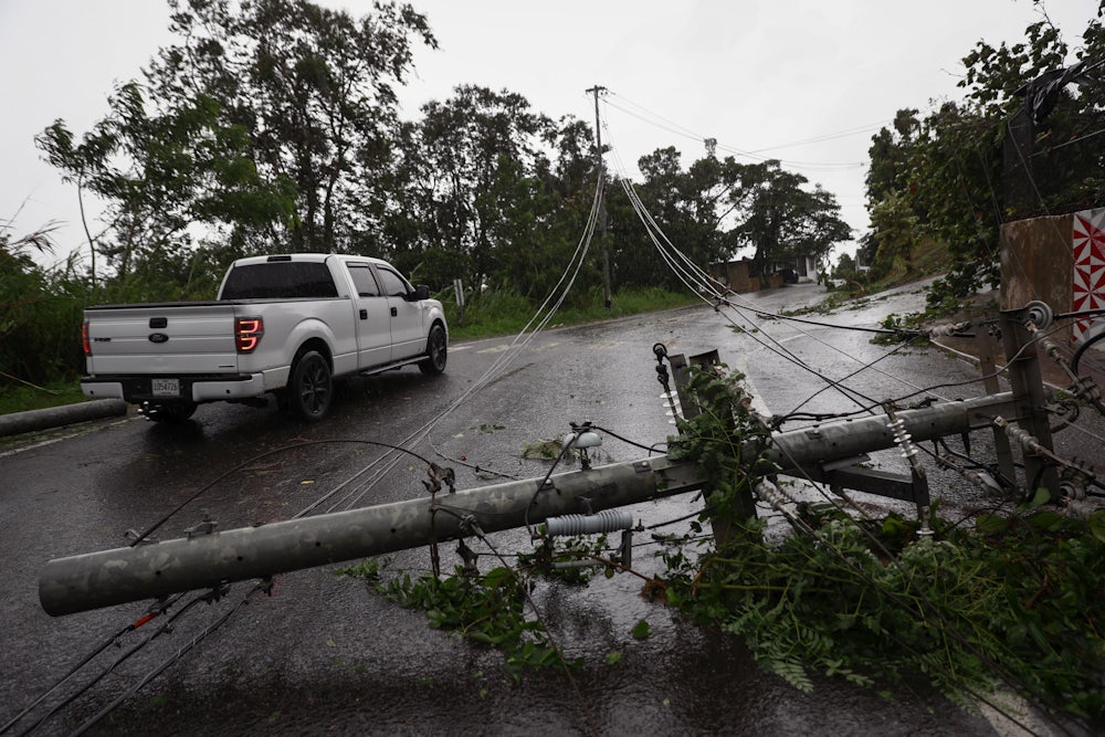 A pickup truck drives next to downed power lines.