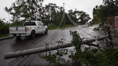 A pickup truck drives next to downed power lines.