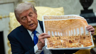Donald Trump holds up a photo of a mock design of his ballroom while sitting in the Oval Office of the White House.