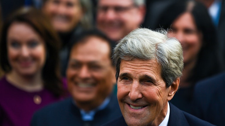 John Kerry smiles in a crowd.