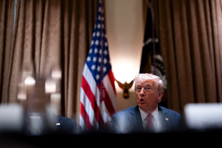 Donald Trump sits at a table and speaks during his Cabinet meeting at the White House