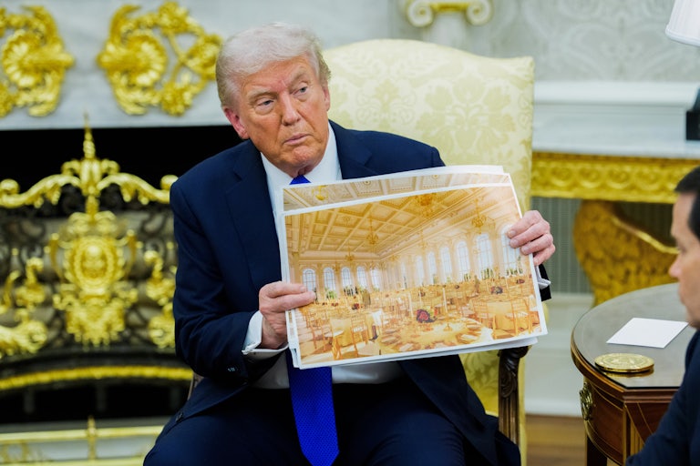 Donald Trump holds up a projected image of his golden White House ballroom, while sitting in his golden Oval Office.