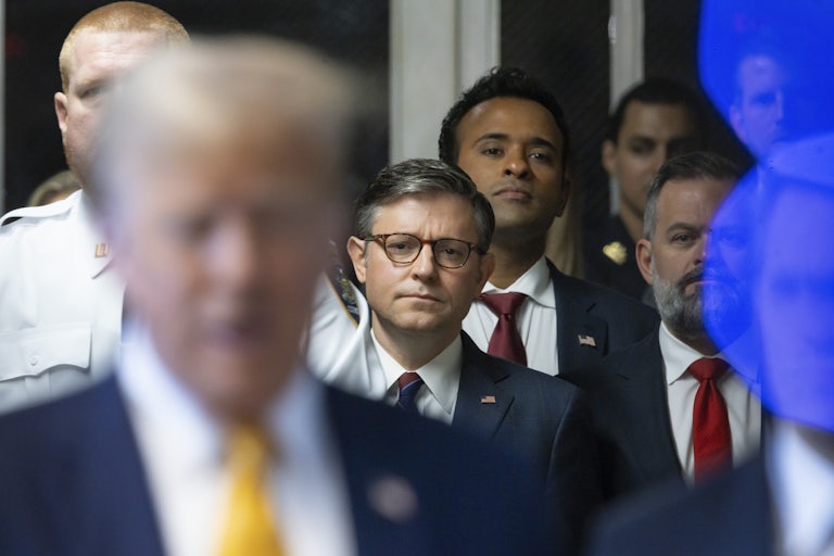 Mike Johnson and Vivek Ramaswamy stand behind Donald Trump as he speaks