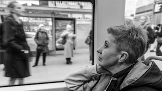 A black and white photograph of Marta Pazdej, a Ukrainian refugee from Lviv, looking out the window at blurry Polish citizens while taking the tram to her boxing class in Warsaw, Poland.
