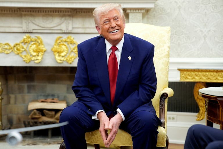 Donald Trump smiles while seated on an armchair in the White House.
