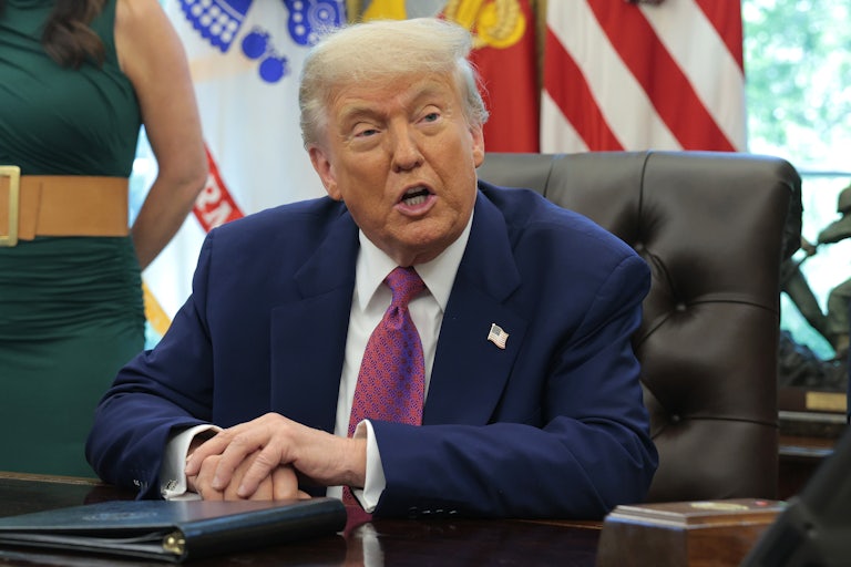 President Donald Trump sits in a chair in the Oval Office.
