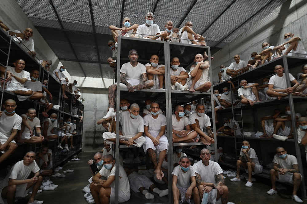 Inmates sit stacked on bunk beds in a massive jail cell.