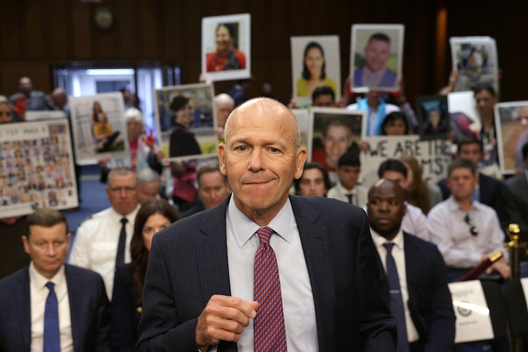 Families of the victims of the Boeing 737 crashes hold up photos of their deceased relatives as Boeing CEO David Calhoun testifies