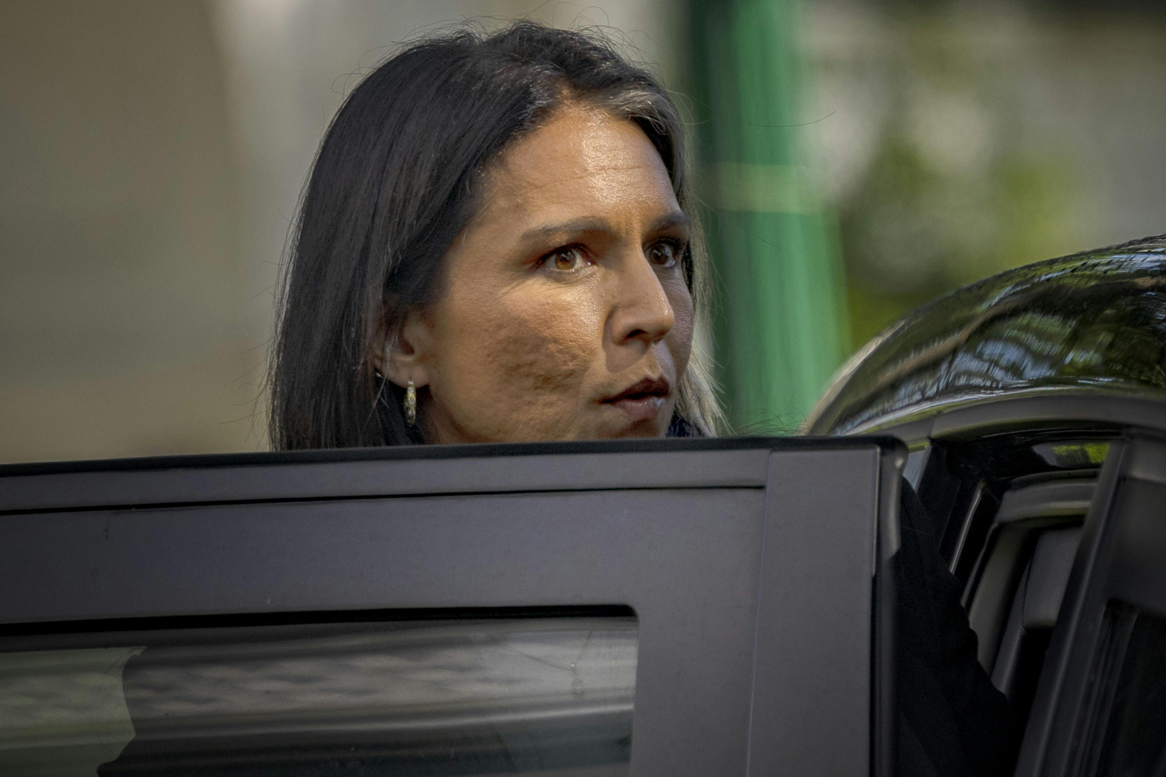 Tulsi Gabbard looks over an open car door as she exits.