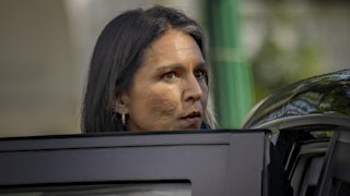 Tulsi Gabbard looks over an open car door as she exits.
