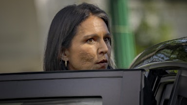 Tulsi Gabbard looks over an open car door as she exits.