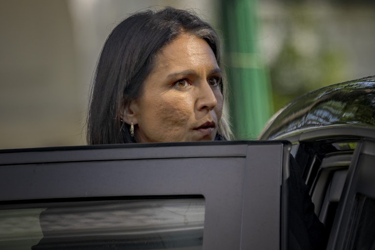 Tulsi Gabbard looks over an open car door as she exits.