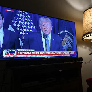 A woman watches FOX News live ahead of Donald Trump's address to the nation following a U.S. special military operation in Venezuela.