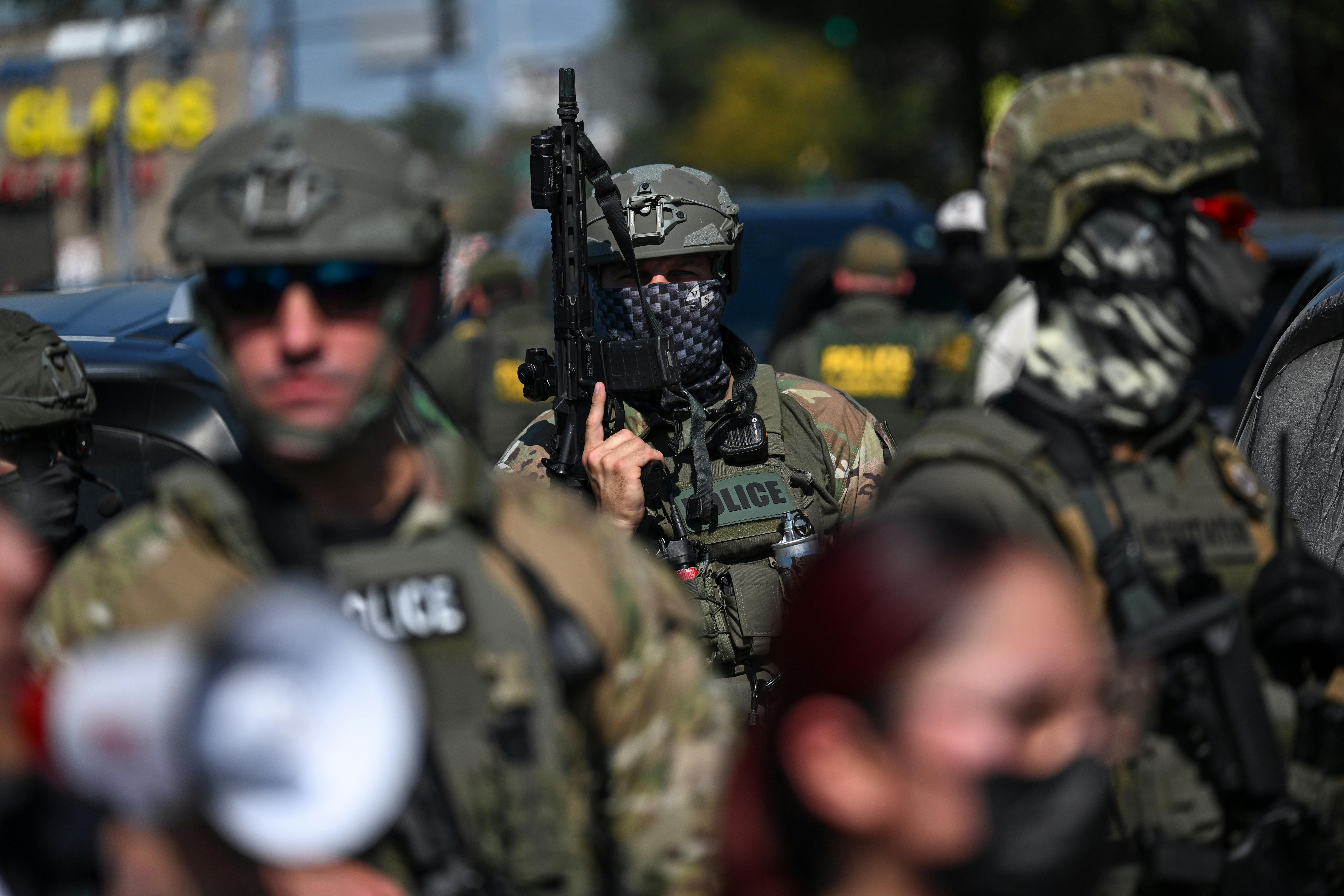A U.S. Immigration and Customs Enforcement officer holds a rifle during a protest in Chicago.