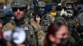 A U.S. Immigration and Customs Enforcement officer holds a rifle during a protest in Chicago.