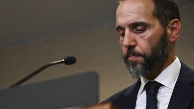 Special counsel Jack Smith looks down while standing at a podium