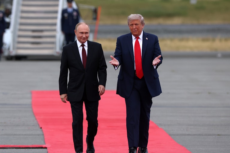 U.S. President Trump and Russian President Vladimir Putin walk down a red carpet.