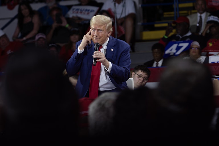 Donald Trump points to his head during a campaign event