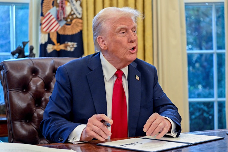 Donald Trump speaks to reporters while signing executive orders in the Oval Office