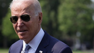 President Biden speaks to the press, wearing sunglasses.
