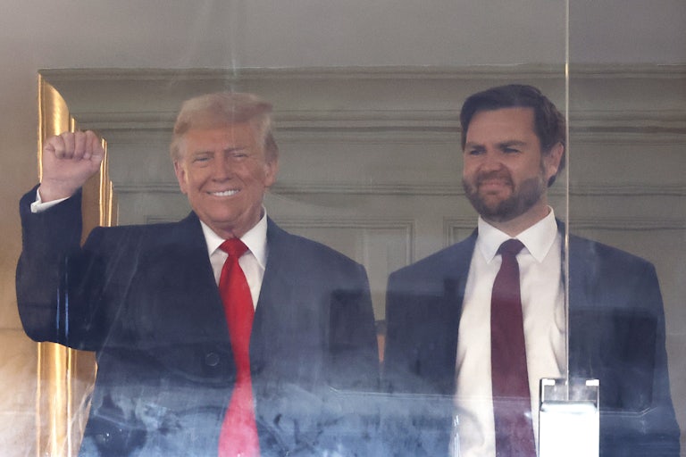 Donald Trump smiles and raises his fist while standing next to JD Vance