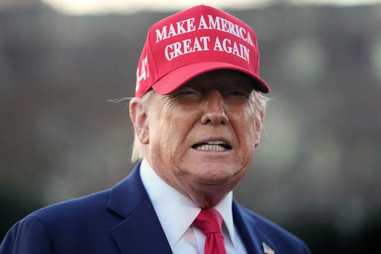 Donald Trump wears a "Make America Great Again" hat and speaks to reporters outside the White House
