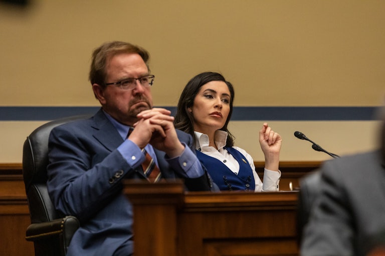Representative Chuck Edwards steeples his fingers together. (Representative Anna Paulina Luna is in the background.)