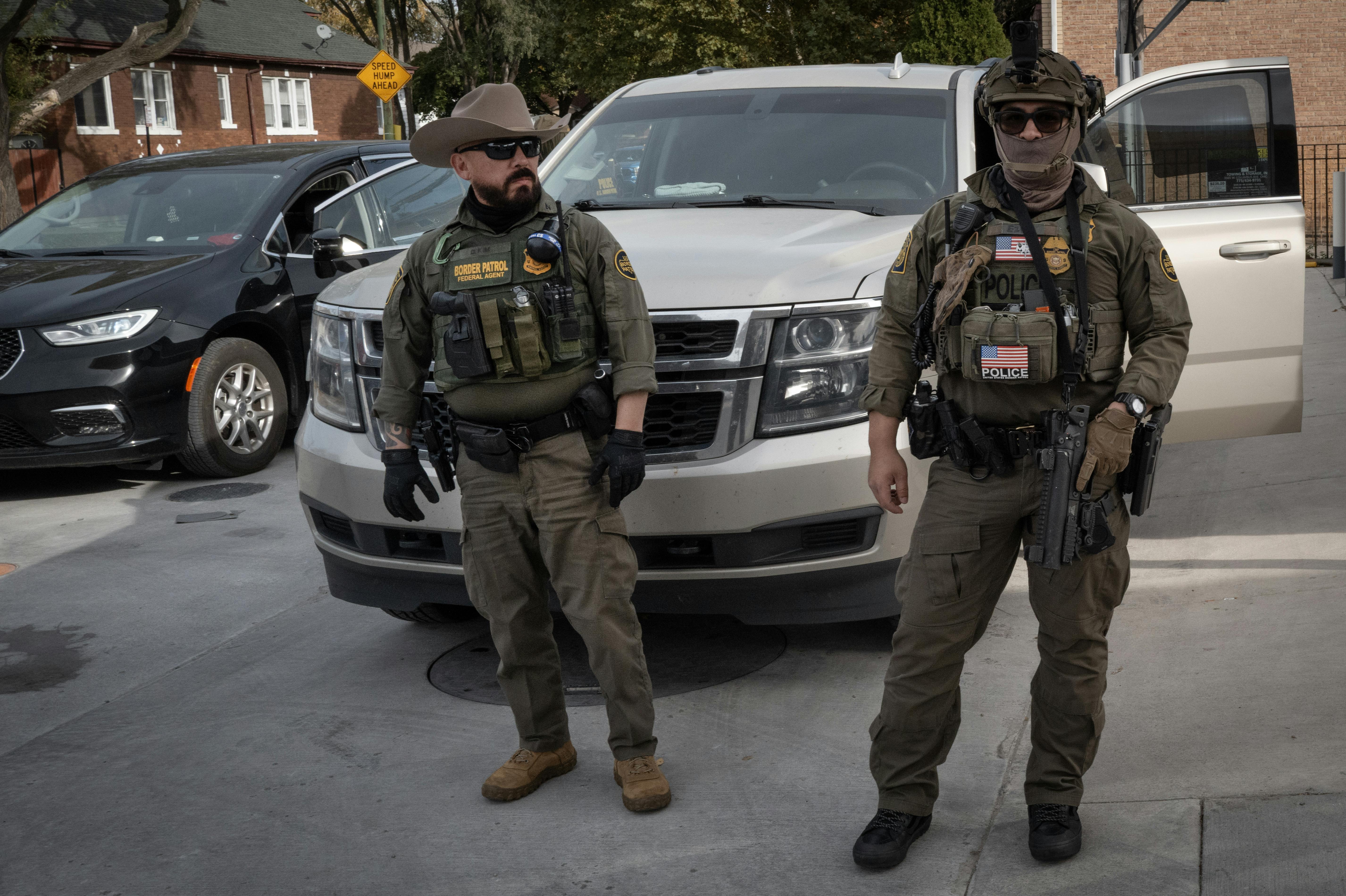 Masked federal immigration agents stand in front of a car in a neighborhood outside Chicago