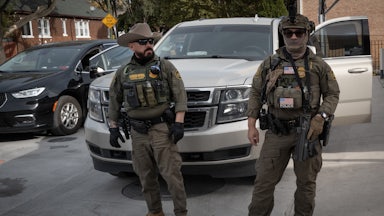 Masked federal immigration agents stand in front of a car in a neighborhood outside Chicago