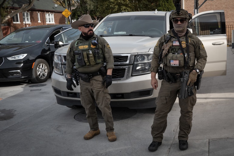 Masked federal immigration agents stand in front of a car in a neighborhood outside Chicago