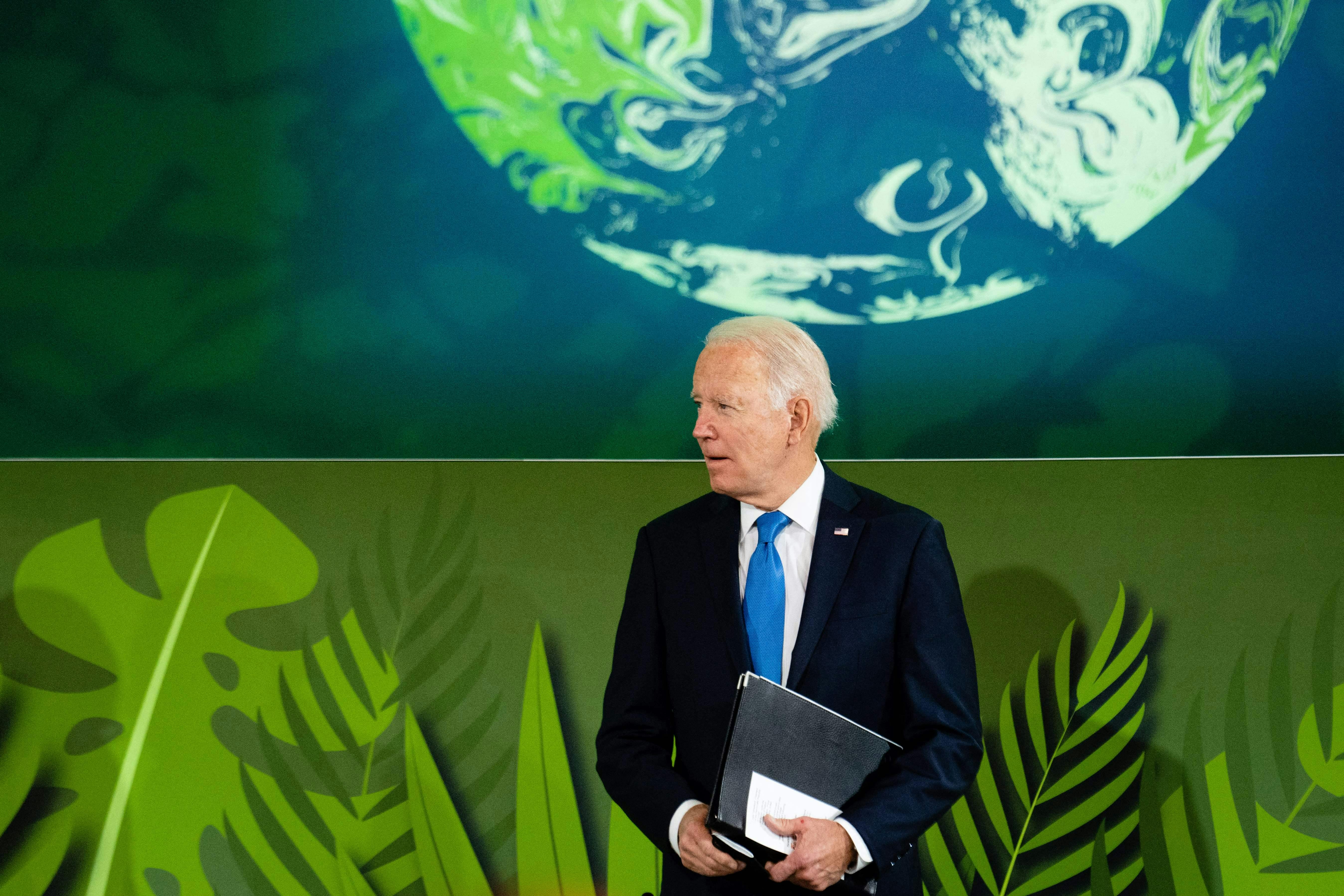 Joe Biden stands, holding a folder.