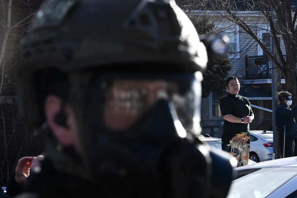 Pastor Jennifer Ikoma-Matzka from Park Ave United Methodist Church watches as ICE agents are confronted after they detained people from a residence on January 13, 2026 in Minneapolis, Minnesota.