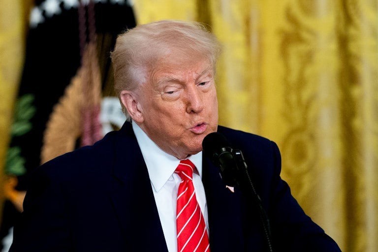 Donald Trump puckers his lips while speaking into a microphone