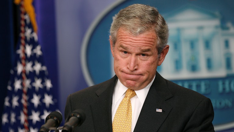 Former President George W. Bush grimaces as he stands behind the lectern in the White House Press Room.
