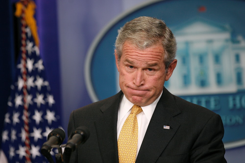 Former President George W. Bush grimaces as he stands behind the lectern in the White House Press Room.