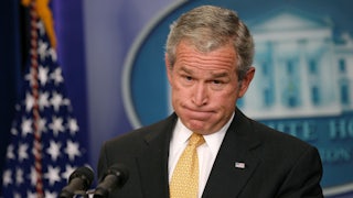 Former President George W. Bush grimaces as he stands behind the lectern in the White House Press Room.