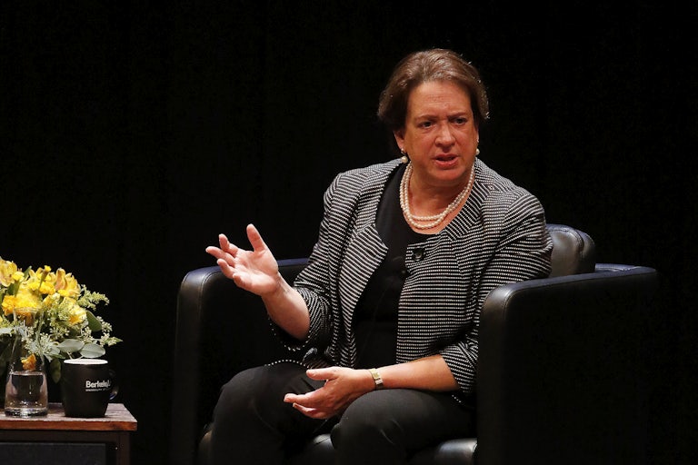Supreme Court Justice Elena Kagan sits in an armchair on stage and gestures while speaking